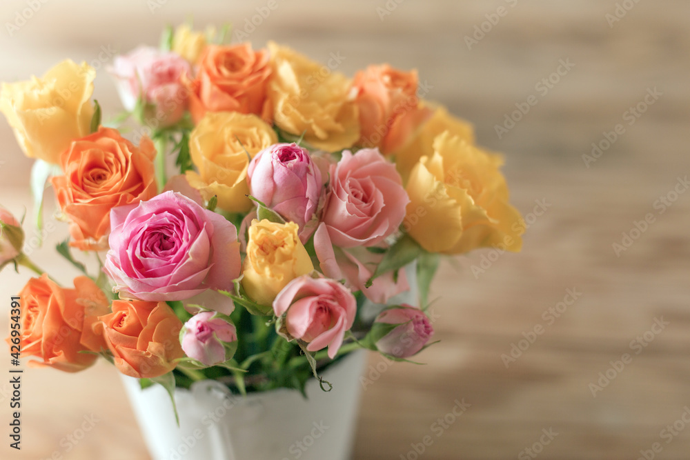 eautiful pink, orenge and yellow roses flowers on old wooden table