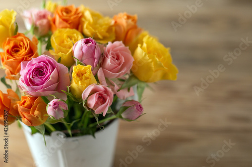 Beautiful pink, orenge and yellow roses flowers on old wooden table