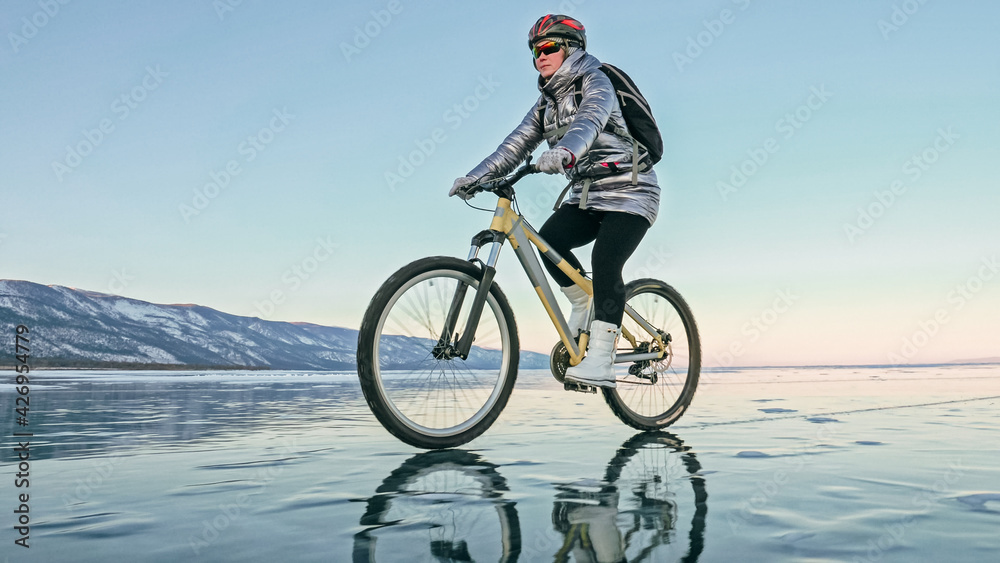 Obraz premium Woman is riding bicycle on the ice. Tires on bike are covered wi