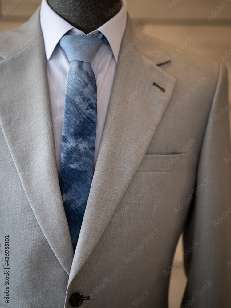 Close up of light grey with ticket pocket suit jacket with blue shirt white collar detail Close up of light grey with ticket pocket suit jacket with blue shirt white collar detail