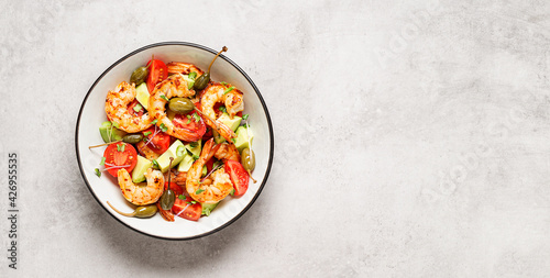 Easy grilled shrimp avocado salad with cherry tomatoes, capers and microgreens. Gray background. Top view. Space for text. 