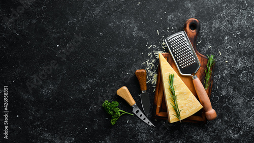 Parmesan. Pieces of Parmesan cheese on black stone background. Top view. Free space for your text.