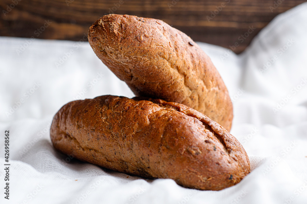 two freshly baked rye bread rolls on a white cloth napkin