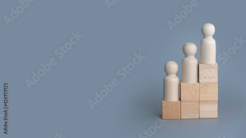 Wooden people on stairs on grey background with copy space.