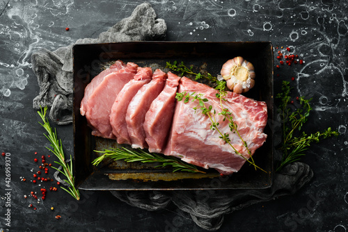 Cuadro en lienzo Raw pork fillet with spices on a black stone background