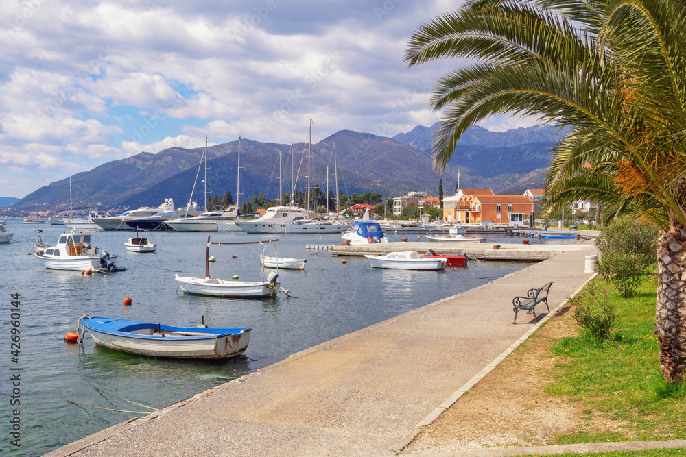 Beautiful Mediterranean landscape with village embankment and fishing boats on water. Montenegro, Adriatic Sea, view of Bay of Kotor  and Seljanovo village near Tivat city