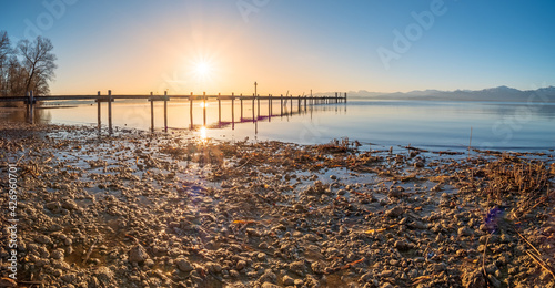 Chiemsee footbridge view during sunrise phase with alp mountain chain at the background