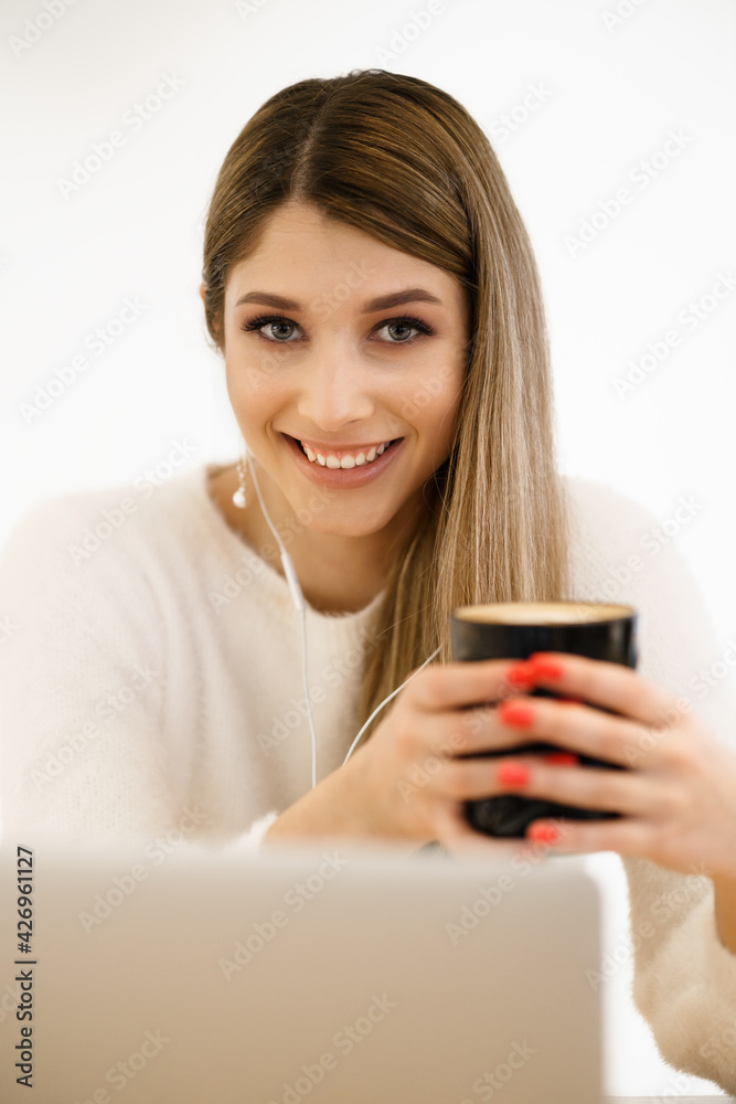 Beautiful young woman in casual clothing using laptop and smiling while working indoors Beautiful young woman in casual clothing using laptop and smiling while working indoors