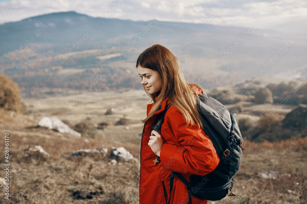 red-haired woman in jacket with backpack travel hiking mountains fresh air
