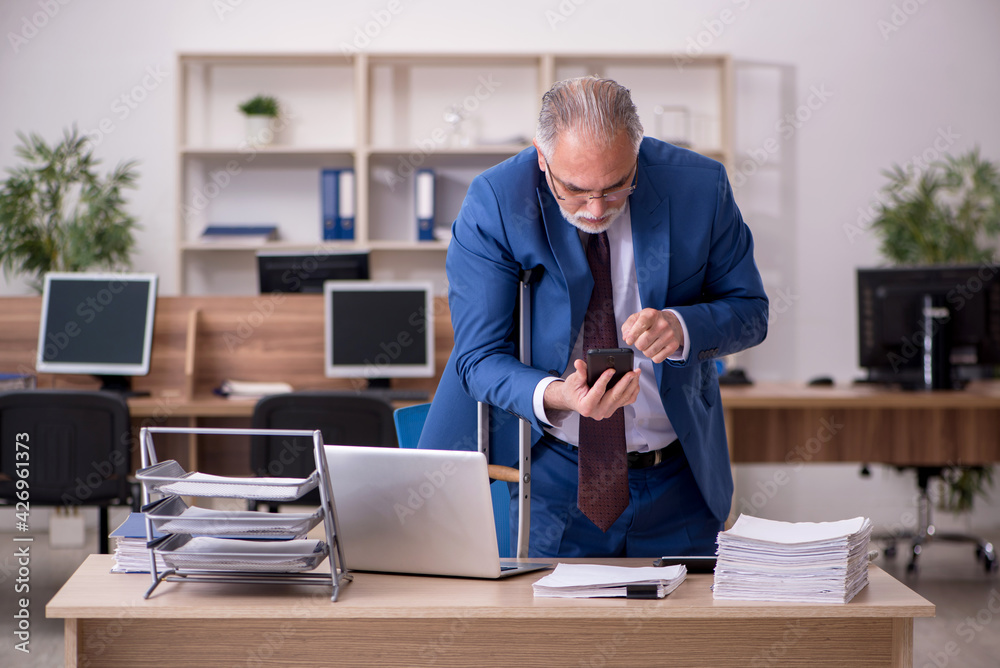 Old businessman employee after accident working in the office Old businessman employee after accident working in the office