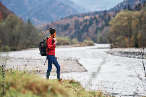 young woman with backpack in the mountains autumn travel tourism landscape shallow water river