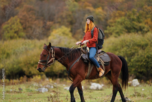 woman hiker with a backpack rides a horse in the mountains nature friendship