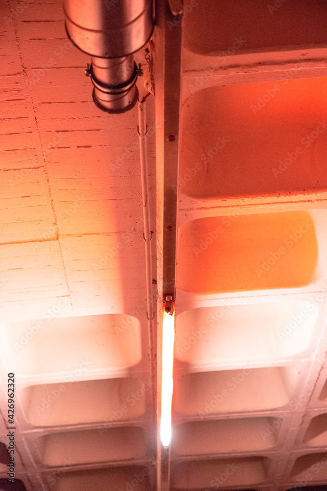 Metallrohr unter weißer Betonkassettendecke mit Neonlichtröhre