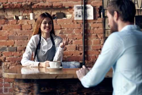 woman waiter brings coffee to a cafe client
