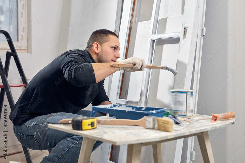 Young adult man painting on a DIY budget renovation of his new home apartment.