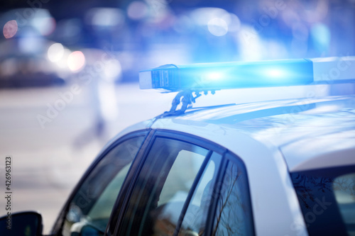 Fototapeta Police car with blue lights on the crime scene in traffic urban environment