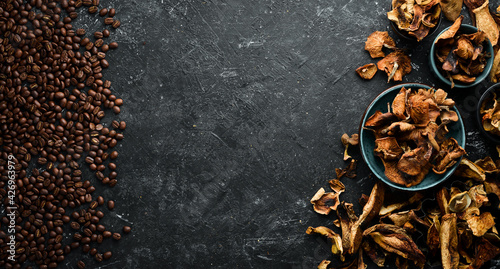 Fragrant coffee beans and dried mushrooms on a black stone background. Organic food, superfood. Top view. Free space for text.