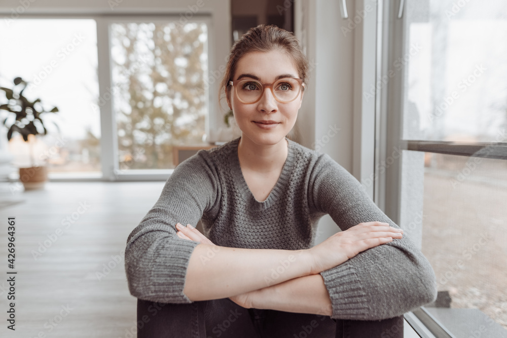 Young woman sitting on the floor thinking with a quiet smile Young woman sitting on the floor thinking with a quiet smile