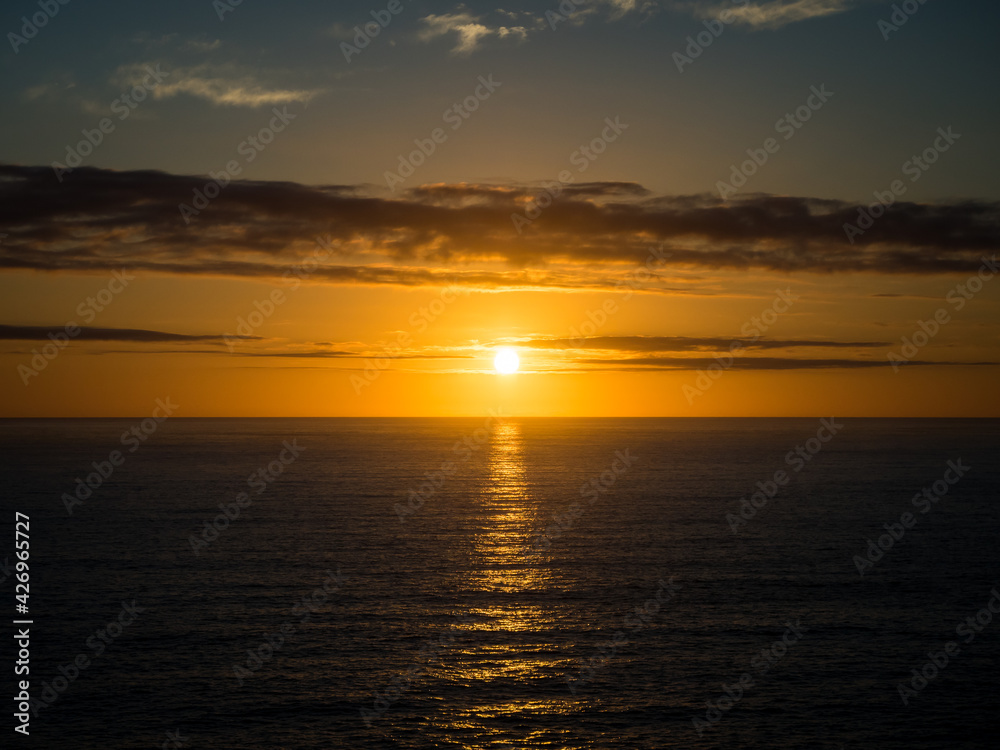 A beautiful golden sunset over the ocean horizon on a warm summers evening.