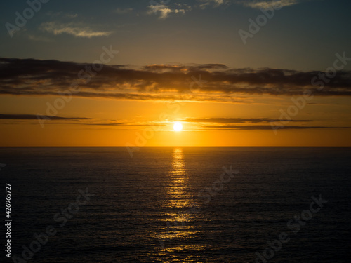 A beautiful golden sunset over the ocean horizon on a warm summers evening. © TristanBalme