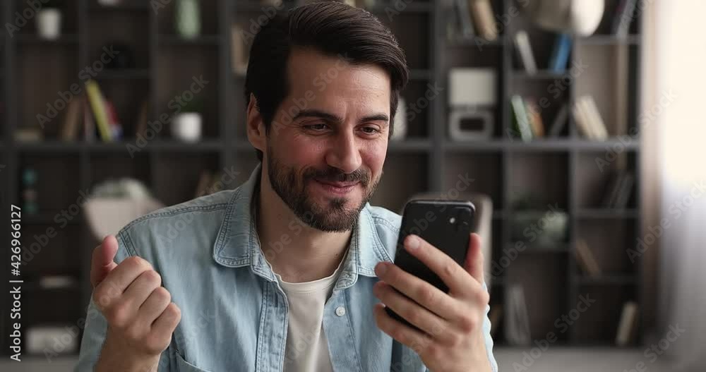 Happy young handsome caucasian man looking at smartphone screen, holding web camera video call zoom conversation with friends or family, talking speaking chatting communicating distantly indoors.
