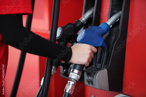  arm of woman with red uniform at the gas station for service , young woman refuel the car or Young girl with fuel pump nozzle at modern gas station