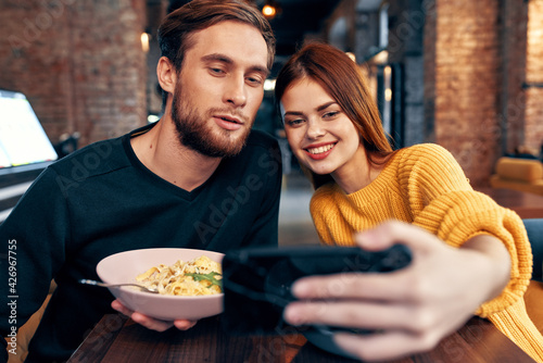 young couple in a restaurant makes a selfie on the phone communication
