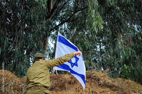 Israeli soldier planted a flag of Israel on top of a hill during a military exercise in army IDF - Israel Defense Forces, Tzahal. Concept: Israeli soldiers, Memorial day,  Independence Day Israel photo