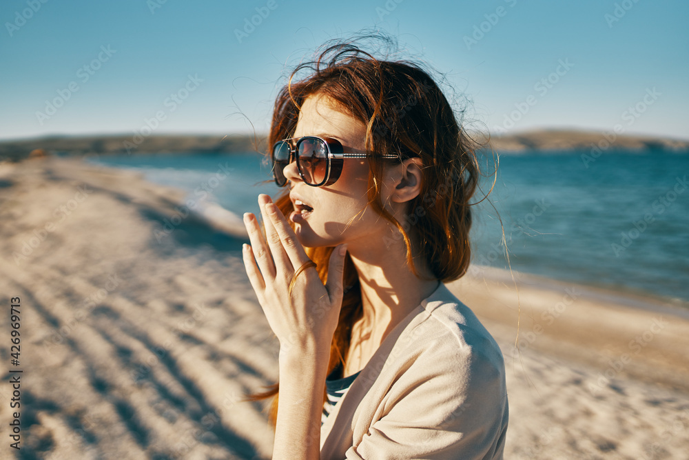 emotional red-haired woman in a jacket holds hands near the face in nature near the sea emotional red-haired woman in a jacket holds hands near the face in nature near the sea