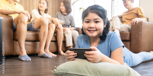 asian daughter child concentrate focus hand use smartphone game online playing with cheerful and fun quarantine stay home in living room home interior background