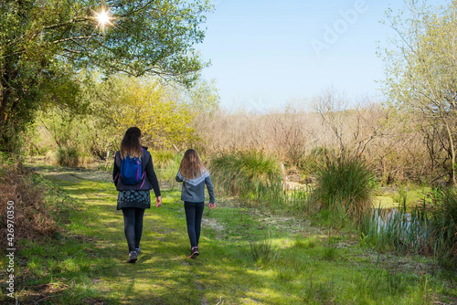 mom and daughter walking in the woods in spring