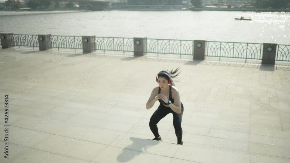 Slow motion Asian sportswoman wearing black sportswear jumping on a stretch ladder Warm up before running a marathon practice every day in the morning in the city with the river before the marathon. Slow motion Asian sportswoman wearing black sportswear jumping on a stretch ladder Warm up before running a marathon practice every day in the morning in the city with the river before the marathon.