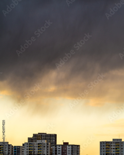 Dark rain clouds over city buildings ar sunset 