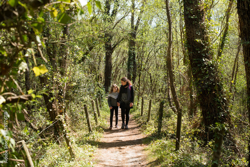 mom and daughter walking in the woods in spring © Image'in