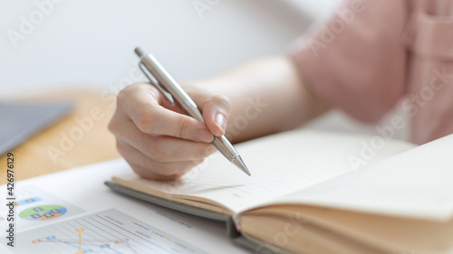 Dollar coins arranged in a slope graph, Blurred image of a businesswoman pressing a calculator, Take a notebook to record information, Saving money for business growth, Save money.