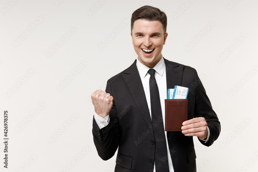 Traveler tourist business man 20s in classic formal black suit hold passport ticket do winner gesture isolated on white office background Passenger travel abroad weekends getaway Air flight journey. Traveler tourist business man 20s in classic formal black suit hold passport ticket do winner gesture isolated on white office background Passenger travel abroad weekends getaway Air flight journey.