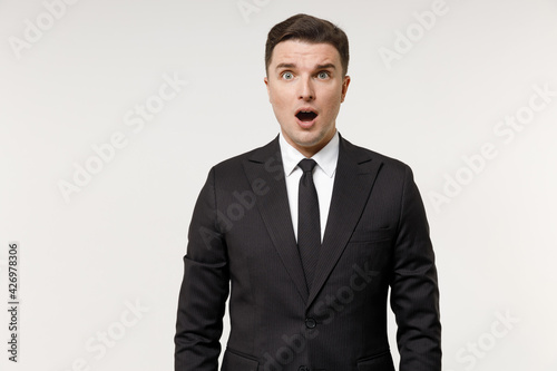 Young shocked caucasian employee business corporate lawyer man 20s in classic formal black grey suit shirt tie work in office look camera with open mouth isolated on white background studio portrait