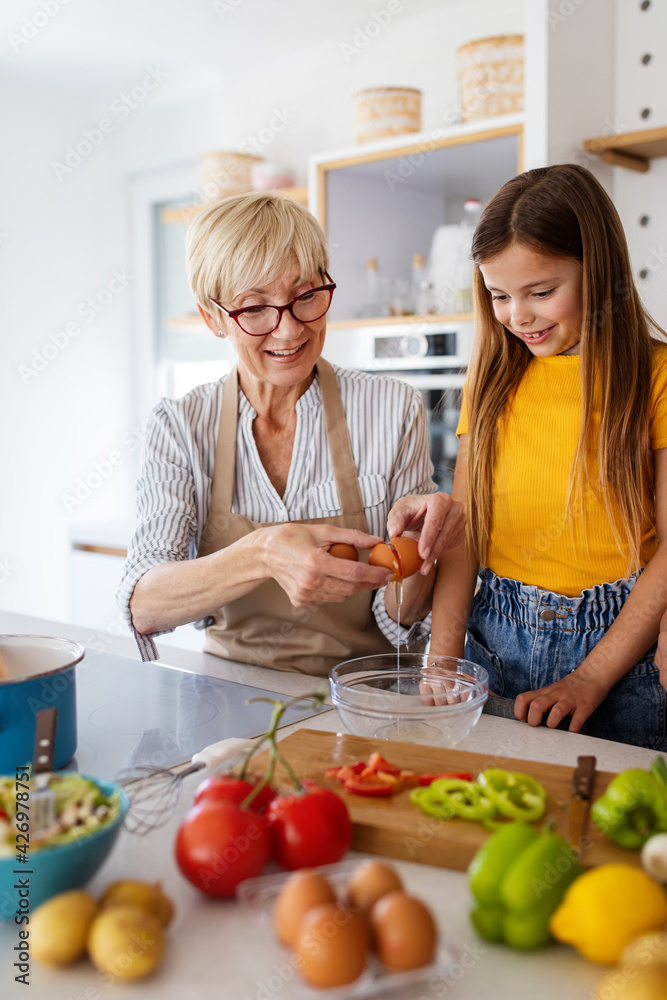 Grandmother and granddaughter are cooking on kitchen. Family fun love generation concept Grandmother and granddaughter are cooking on kitchen. Family fun love generation concept