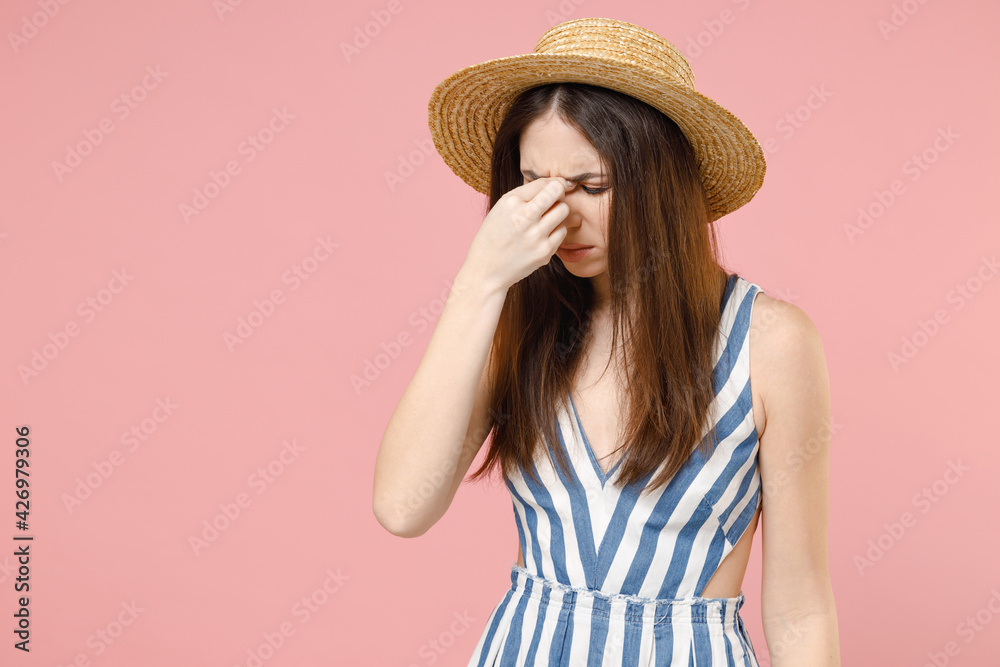 Young tired sad puzzled troubled caucasian woman 20s wear summer clothes dress straw hat rub put hand on nose bridge nose isolated on pastel pink background studio portrait. People lifestyle concept. Young tired sad puzzled troubled caucasian woman 20s wear summer clothes dress straw hat rub put hand on nose bridge nose isolated on pastel pink background studio portrait. People lifestyle concept.