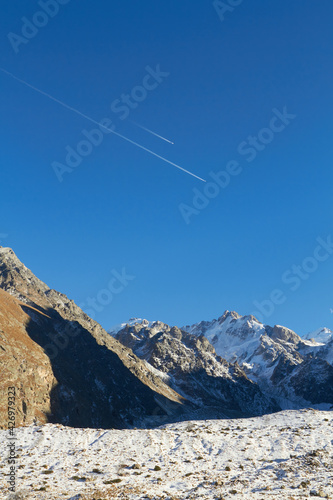The trail of the plane against the blue sky in the Bezengi mountains of Kabardino-Balkaria