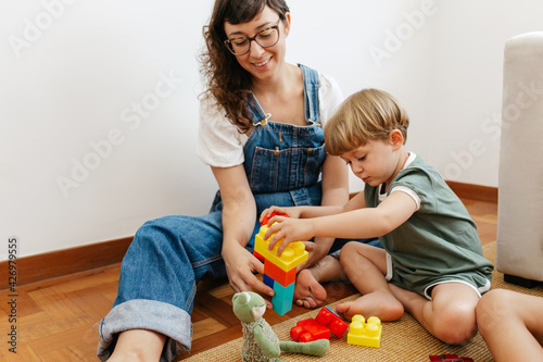 Child playing colorful blocks game with mother