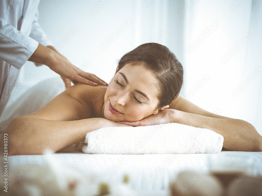 Beautiful brunette woman enjoying back massage with closed eyes comfortable and blissful. Spa and medicine concept Beautiful brunette woman enjoying back massage with closed eyes comfortable and blissful. Spa and medicine concept