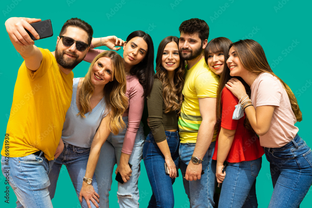 Obraz premium Seven smiling young friends taking a selfie together- group of kids isolated on light blue background