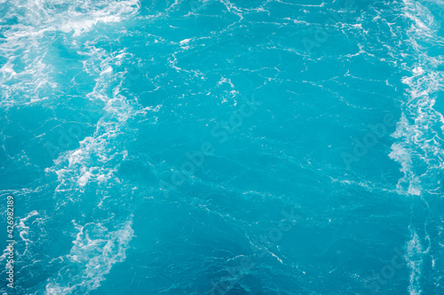 Surface of the sea. Natural texture of blue foaming sea water. Turquoise ocean water background.