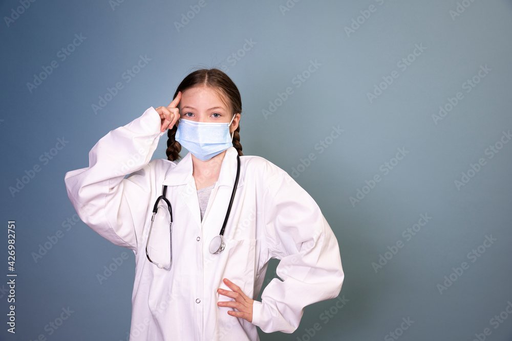 pretty young girl with 2 braids dressed as a doctor with protective mask and stethoscope in front of blue background pretty young girl with 2 braids dressed as a doctor with protective mask and stethoscope in front of blue background