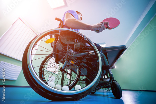 Fototapeta Naklejka Na Ścianę i Meble -  Disabled man in a wheelchair play at table tennis. Tennis balls fixed in a wheel