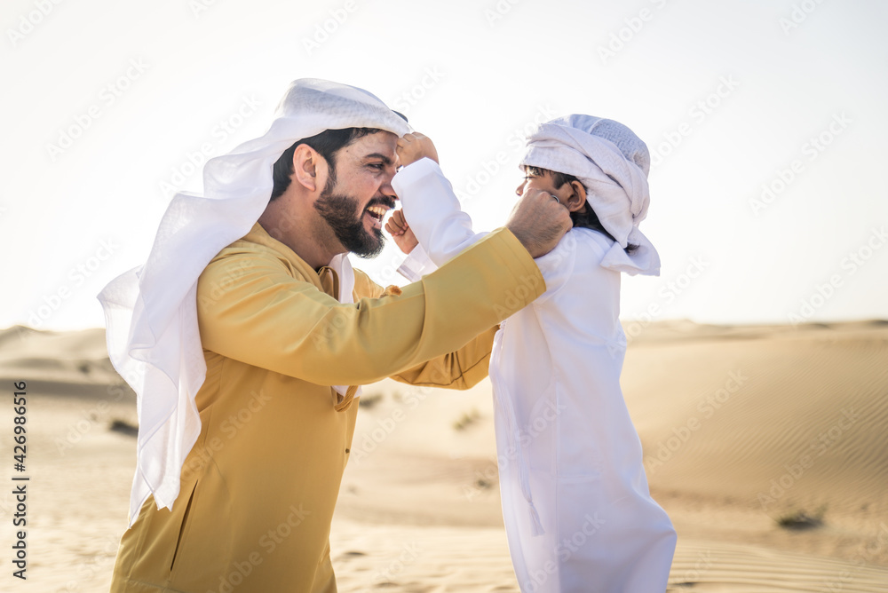 Arabian man and son playing in the desert Arabian man and son playing in the desert