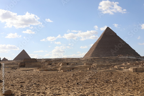 The great pyramids of giza. Tourists in the historic city. Beautiful landscape on a sunny day. View of walking people on a cloudy morning. Travel to African continent. UNESCO World Heritage Site.