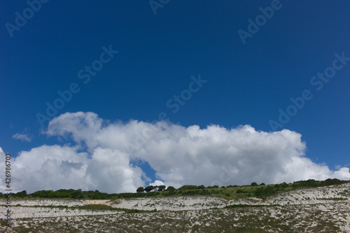 White clouds and blue sky above white cliffs of Dover in the United Kingdom seen from the sea 