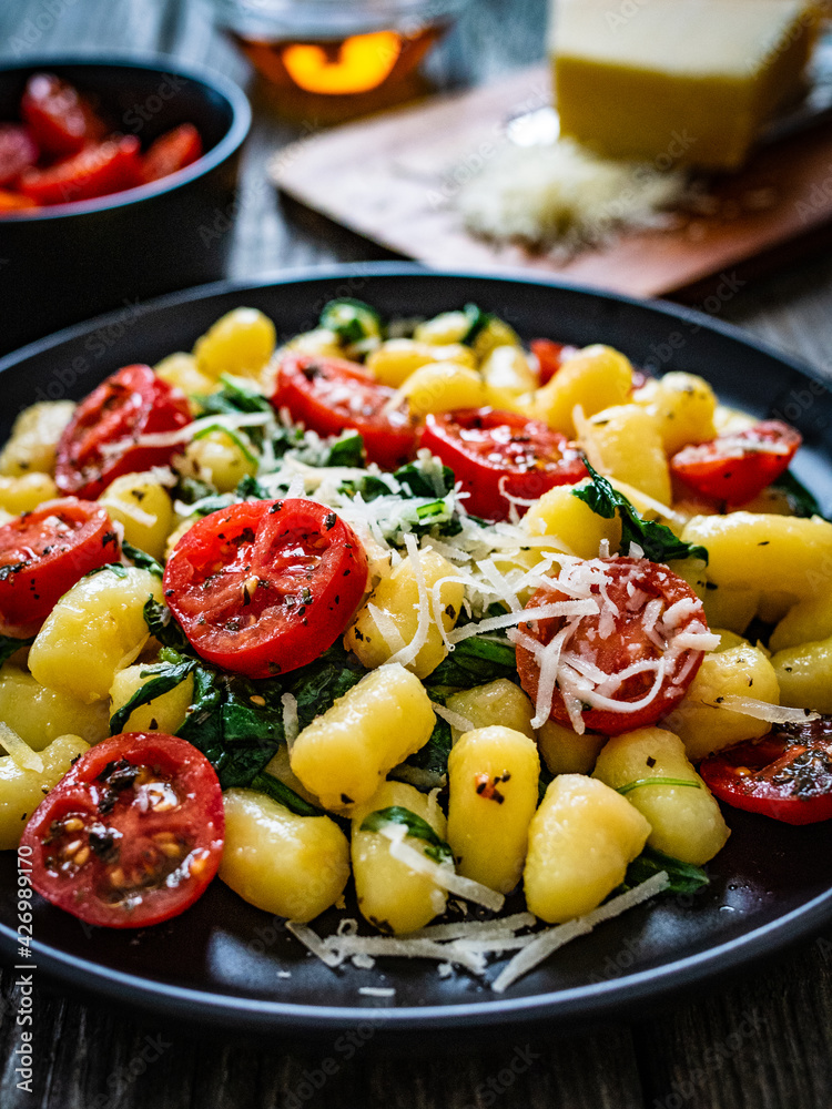 Gnocchi with tomato, spinach and parmesan on wooden table
Gnocchi with tomato, spinach and parmesan on wooden table